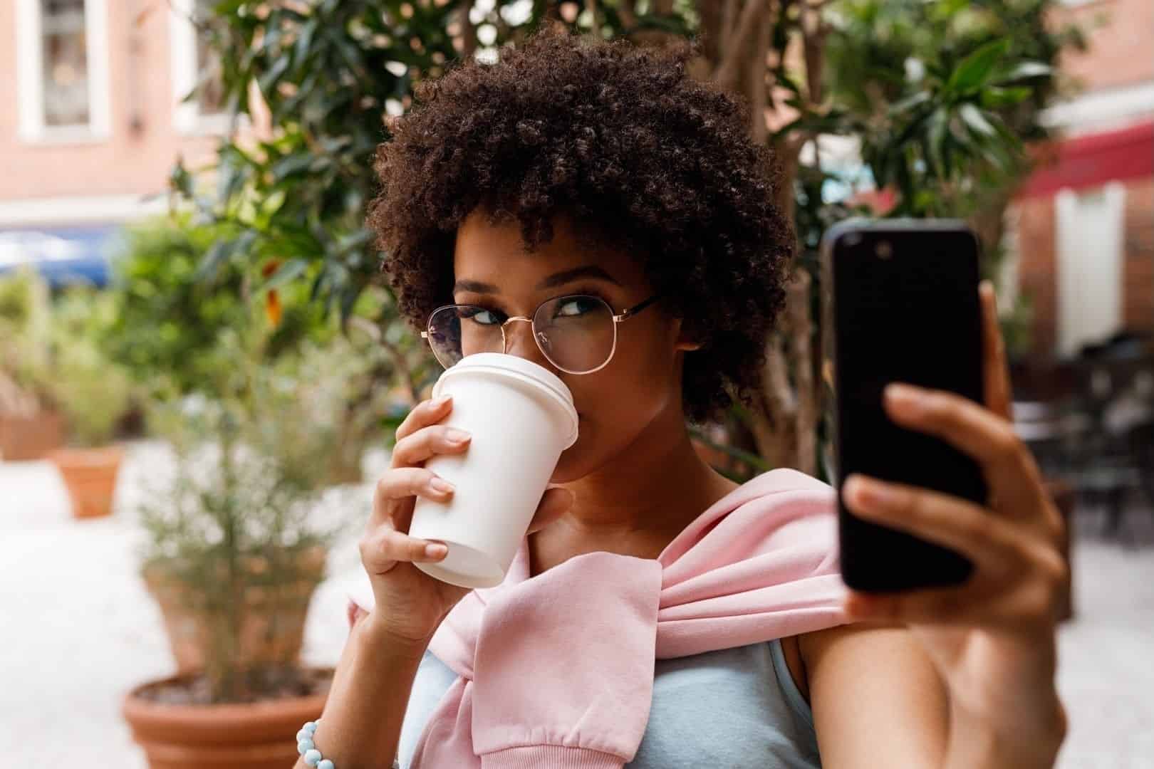 woman with coffee cup looking at phone