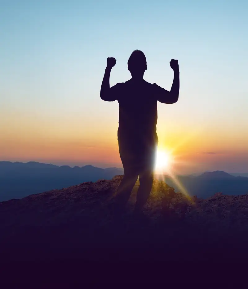 person on top of a mountain with sun behind them