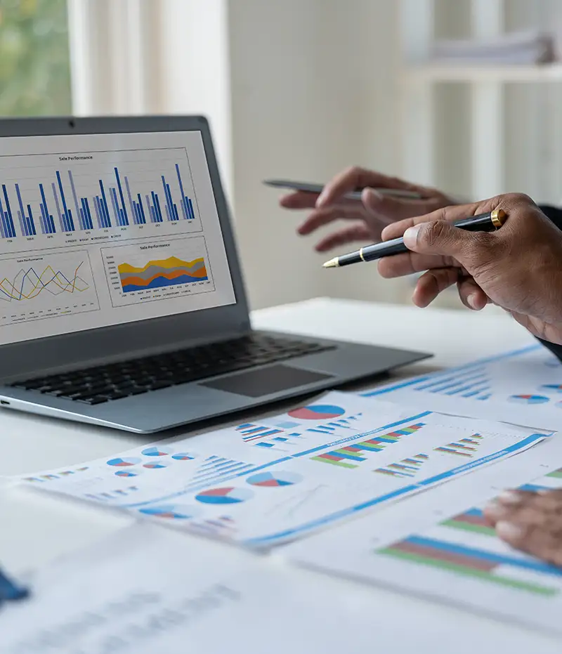 people pointing to analytics on computer with charts on the table