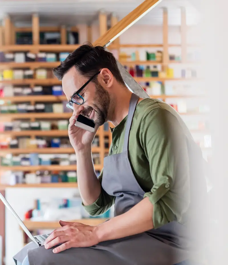 man on the phone while looking at a laptop