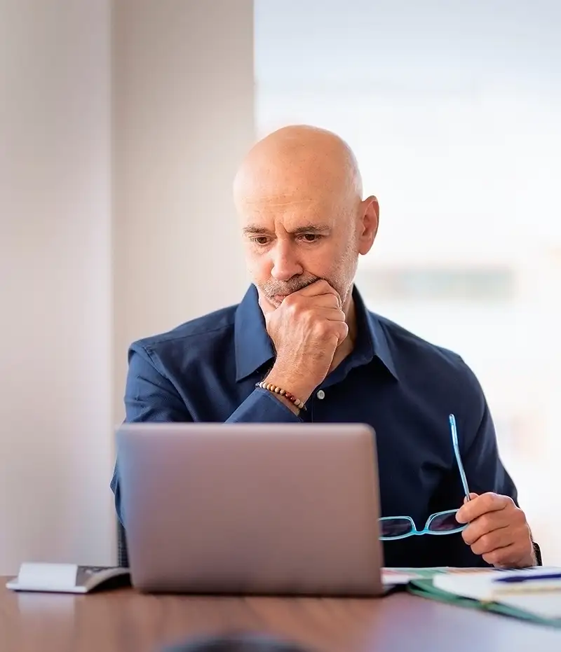 man holding glasses thinking while on computer